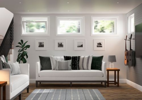 Basement hopper windows above a modern living room with white sofas, patterned pillows, a striped rug, potted plant, and wall-mounted guitars.