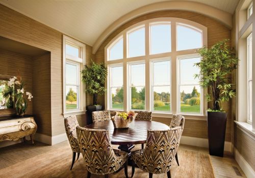 Double hung windows with an arched top in a dining room, featuring a round table with patterned chairs, potted plants, and a scenic outdoor view.