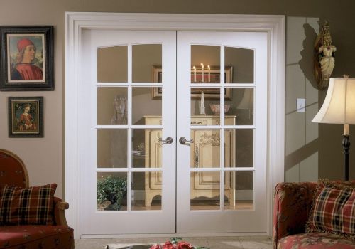 Interior view of white French doors with divided glass panes and satin nickel handles, adding classic elegance and natural light between two living spaces.