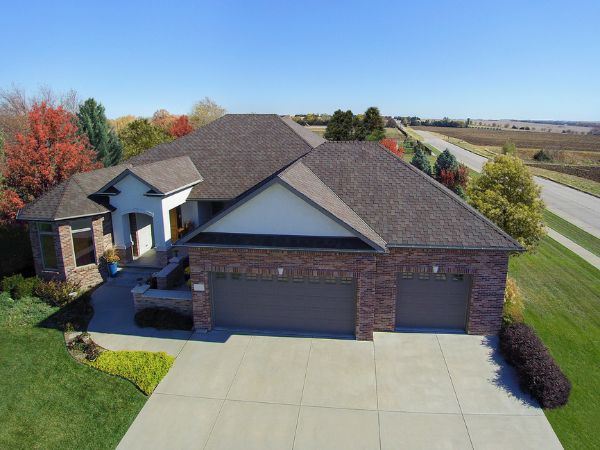 House with Malarkey Windsor Heather shingle roof in grayish-brown, featuring brick siding and autumnal surroundings