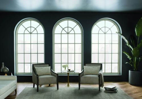Special shapes windows with three arched panels in a modern living room with dark walls, two armchairs, a small table, and a large potted plant.