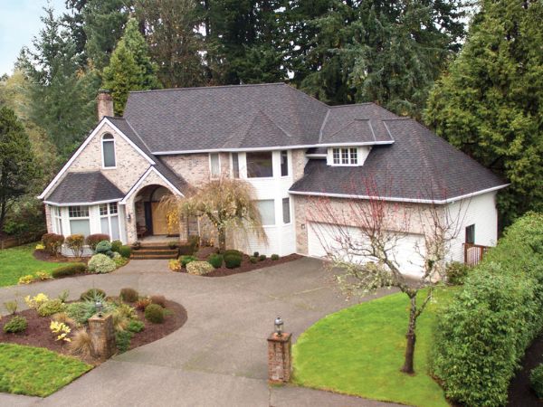 House with Malarkey Windsor Black Oak shingle roof in deep black with oak accents, featuring landscaped greenery