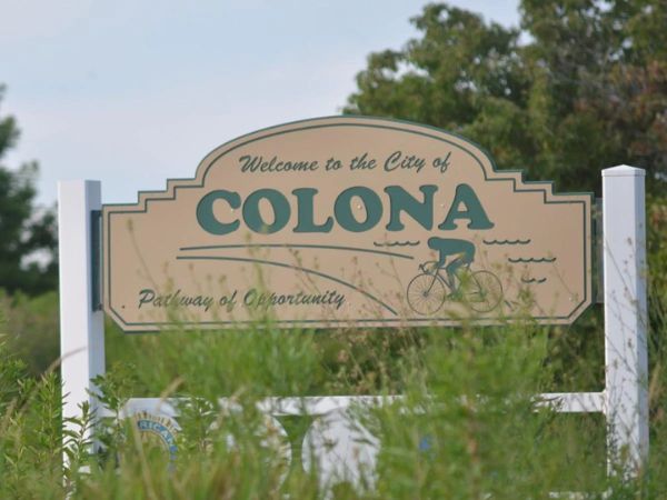 Welcome to the City of Colona sign with a cyclist graphic and 'Pathway of Opportunity' slogan, for a Colona, IL roofing, windows, and siding company.