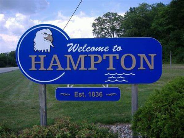 Welcome to Hampton sign with an eagle graphic and 'Est. 1836' text, for a Hampton, IL roofing, windows, and siding company.
