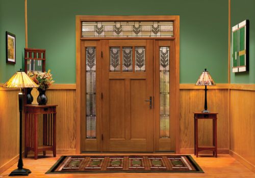 Wood entry door with decorative glass sidelites on both sides and a matching transom window above, enhancing natural light and adding craftsman-style elegance to the foyer.