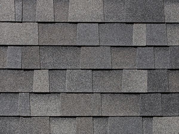 Close-up of Malarkey Storm Grey asphalt shingles in medium-dark gray with speckled texture for robust roofing