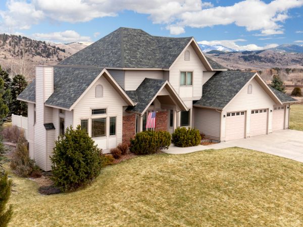 House with Malarkey Storm Grey asphalt shingle roof in medium-dark gray, set against a mountainous backdrop