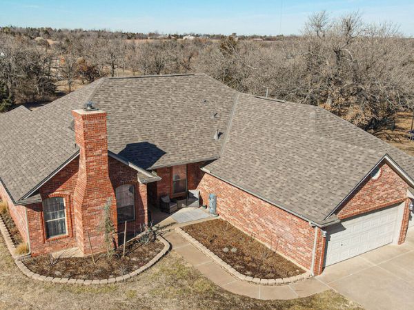 House with Malarkey Weathered Wood asphalt shingle roof in gray-brown, featuring brick siding and a winter landscape